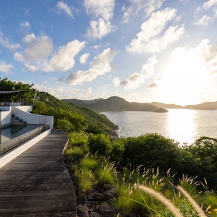 Spectacular hillside property featuring infinity pool and expansive deck overlooking pristine tropical coastline and mountain vistas.