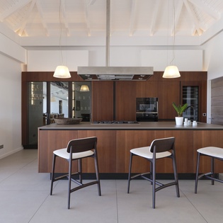 Gather at the sleek kitchen island with stylish bar seating, where modern design meets warm wood tones under beautiful vaulted ceilings with natural light.