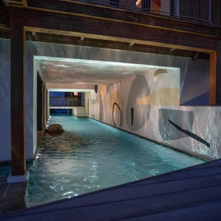 Slip into this stunning indoor pool where warm lighting creates a serene cave-like atmosphere for your evening swim.