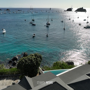 Stunning elevated vista of crystal-clear turquoise waters dotted with anchored sailboats and yachts in this pristine Caribbean bay.