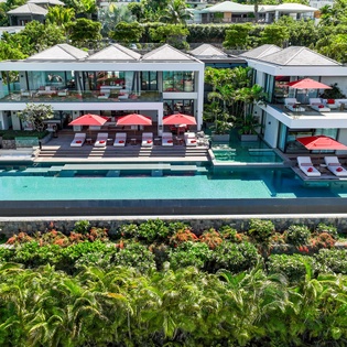 Stunning modern villa with expansive infinity pool and tropical gardens nestled in lush hillside landscape.