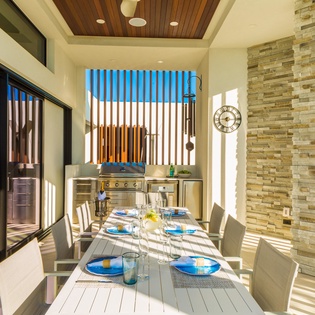 Gather around the outdoor dining table where a built-in grill awaits your culinary adventures. Sunlight filters through slatted screens, casting warm patterns across the setting—perfect for leisurely meals in your private courtyard.