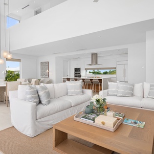 Unwind in your luxurious open-plan living space, where soaring white beams frame panoramic views and plush seating invites endless relaxation.