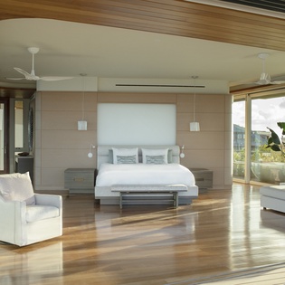 Relax in your stunning modern bedroom with sleek furnishings, warm wood accents, and floor-to-ceiling windows flooding the space with natural light.