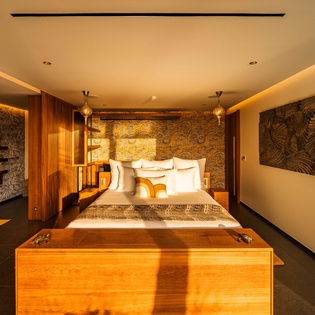 Unwind in your luxurious suite where warm lighting and natural stone create a serene sanctuary. Plush linens and artistic touches invite restful nights after your adventures.