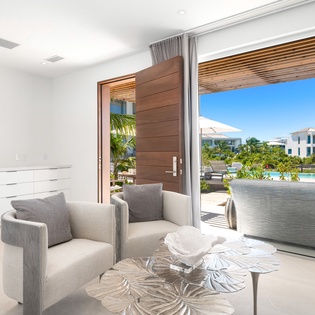 Relax in your elegant living space with sleek furnishings and stunning views of tropical gardens through expansive glass doors.