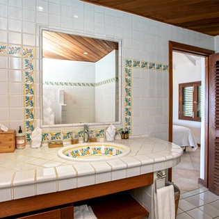 Unwind in your private bathroom featuring handcrafted tile work, warm wood accents, and a colorful hand-painted sink that adds Mediterranean charm to your daily routine.