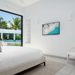 Step into your serene retreat with a plush bed, calming coastal art, and a private pool just beyond your window—your perfect escape awaits.