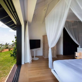 Wake up to the ocean just beyond your bed, where soft white linens and breezy curtains frame unobstructed sea views from your private, open-air retreat.