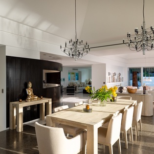 Your elegant dining space flows seamlessly into the modern kitchen, where dramatic chandeliers cast warm light over intimate dinners.