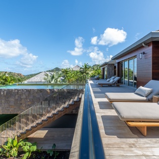 Unwind on your private terrace with plush loungers overlooking tropical hills and azure skies.
