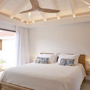 Drift off under soaring beamed ceilings in your serene bedroom, where natural light and garden views create the perfect peaceful retreat.