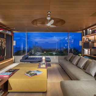 Sink into plush seating in your sophisticated living room, where floor-to-ceiling windows frame stunning views while built-in shelving holds your favorite reads.