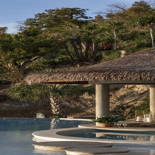Tropical paradise with pristine pool, thatched pavilion, and lush jungle surroundings creating the perfect escape.