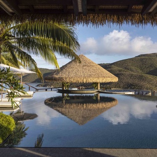 Stunning infinity pool with swim-up bar creates your perfect tropical escape, surrounded by lush palms and mountain views.
