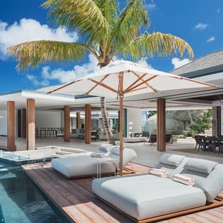 Luxurious poolside loungers await under tropical palms and elegant umbrellas in this stunning outdoor paradise.