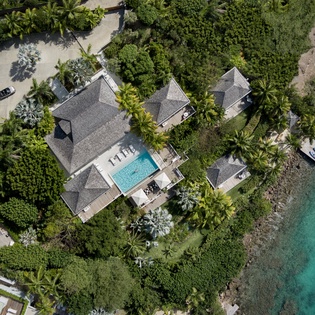 Luxury beachfront villa with private pool surrounded by lush tropical gardens, steps from pristine turquoise waters.