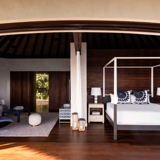 Unwind in your elegant canopy bed suite with rich wood floors and a cozy lounge area perfect for peaceful evenings.
