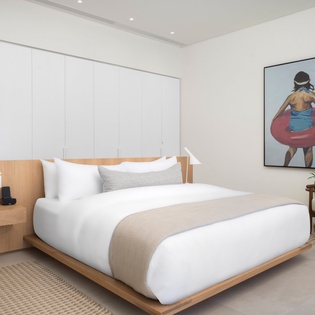 Unwind in your peaceful retreat with crisp white linens, modern minimalist design, and artistic touches that create the perfect sanctuary for rest.