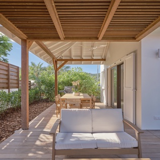 Unwind on your private terrace with comfortable seating under natural timber shade, perfect for peaceful moments overlooking lush gardens.