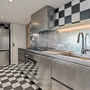 Your sleek stainless steel kitchen features modern appliances and bold checkerboard flooring, creating a stylish space for culinary adventures.