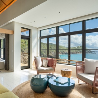 Unwind in your elegant living space with breathtaking ocean views through floor-to-ceiling windows that frame the turquoise waters perfectly.