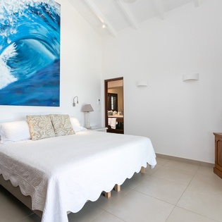 Sink into crisp white linens in your airy bedroom, where ocean-inspired art sets a serene tone for your tropical escape.