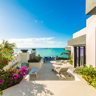 Modern tropical villa with stunning turquoise ocean views, lush flowering gardens, and multiple sun-drenched lounging areas perfect for your Caribbean escape.