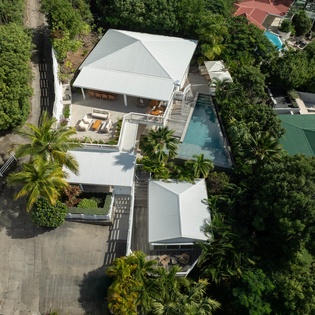 Tropical villa with private pool nestled among lush greenery in a quiet residential neighborhood.