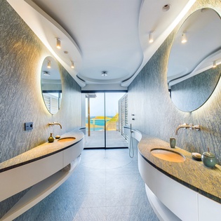 Unwind in your private spa-like bathroom with dual vanities, natural stone accents, and dramatic lighting.