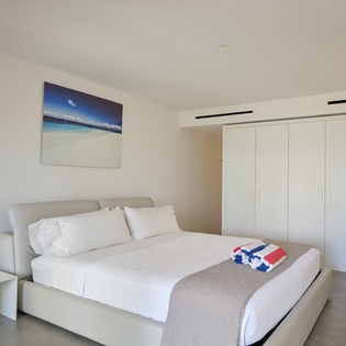 Sink into crisp white linens in your modern bedroom, where ocean artwork and clean lines create the perfect retreat.