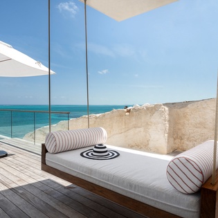 Drift away on your private hanging daybed while turquoise waters stretch endlessly before you—pure beachfront bliss.