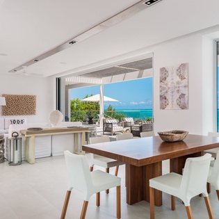 Your elegant dining space opens to breathtaking ocean views, where modern design meets tropical paradise through floor-to-ceiling windows.
