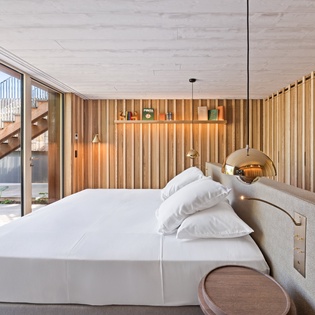 Wake up in this stunning bedroom where warm wood meets crisp linens, with floor-to-ceiling windows framing your private outdoor space.