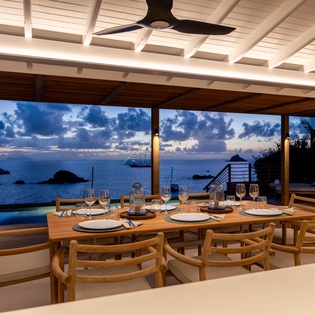 Savor dinner with ocean views as twilight paints the sky, while gentle ceiling fans keep you comfortable in this elegant beachfront dining space.
