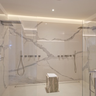 Step into your luxurious marble-lined shower sanctuary with dual rainfall showerheads and elegant spa-inspired design for ultimate relaxation.