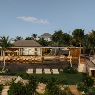Stunning tropical villa with infinity pool, loungers, and lush palm surroundings creating the perfect island retreat atmosphere.