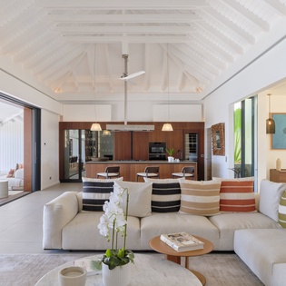 Sink into plush seating under soaring vaulted ceilings as natural light floods your open-plan living space, seamlessly blending indoor luxury with tropical outdoor views.