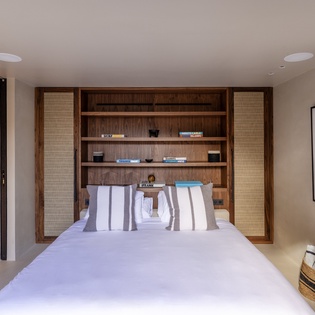 Sink into plush white linens surrounded by warm wood shelving filled with books for your evening reading pleasure.