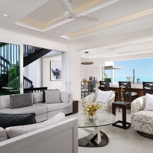 Relax in this stunning open-concept living space with soaring ceilings, modern furnishings, and breathtaking ocean views that create your perfect island retreat.