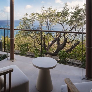 Stunning sea views await from your private balcony where turquoise waters meet lush tropical scenery through sleek glass railings.