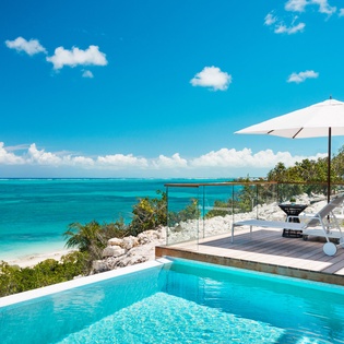 Stunning oceanfront pool deck with turquoise waters stretching to the horizon and pristine beach access.