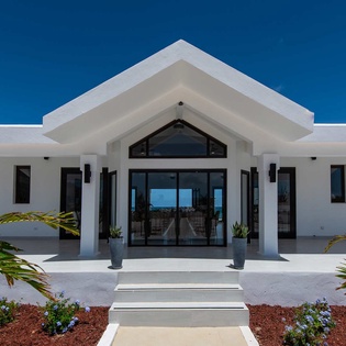 Modern white exterior showcases clean architectural lines and tropical landscaping, framing a grand entrance that sets the stage for your island escape.