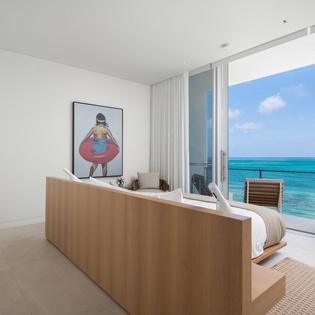 Wake up to stunning turquoise waters from your modern bedroom, where floor-to-ceiling windows frame endless ocean views and invite sea breezes.