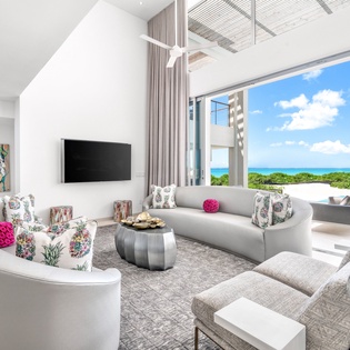 Relax in your bright living room where modern comfort meets stunning ocean views through floor-to-ceiling windows.