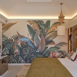 Unwind in your tropical sanctuary with stunning botanical murals, plush bedding, and warm ambient lighting creating the perfect retreat.