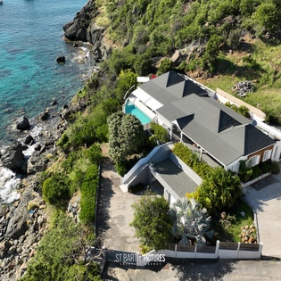 Stunning oceanfront villa with crystal-clear waters and sailboats anchored just steps from the property.