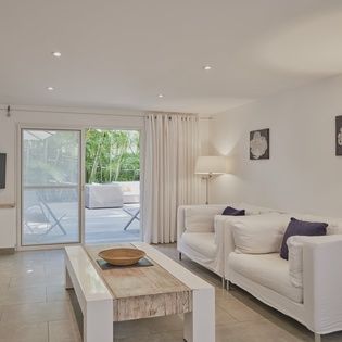 Sink into plush white sofas in your bright living space, where sliding doors reveal a peaceful terrace perfect for morning coffee.