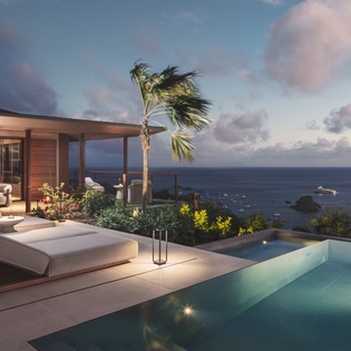 Modern oceanfront villa features an infinity pool overlooking the sea with comfortable loungers and tropical landscaping.