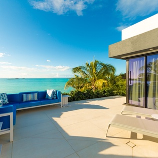 A spacious terrace with ocean views and vibrant blue lounges invites you to soak up the sun and sea breeze under a brilliant blue sky.